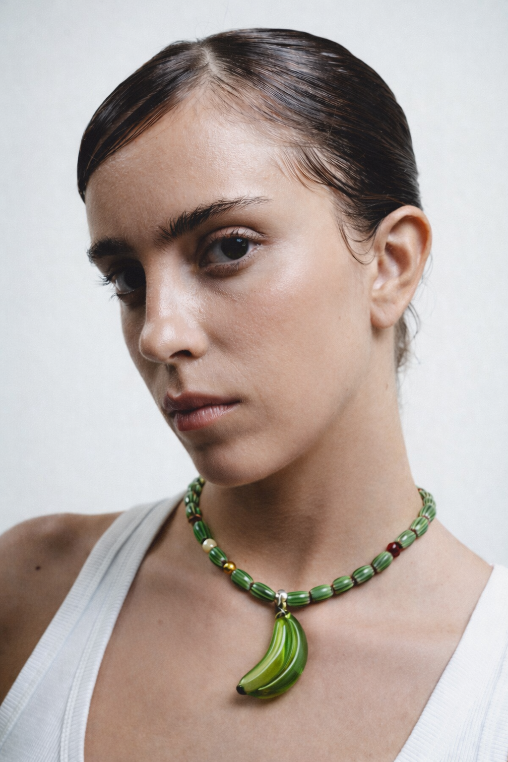 Necklace with green beads and a banana-shaped pendant on a white background