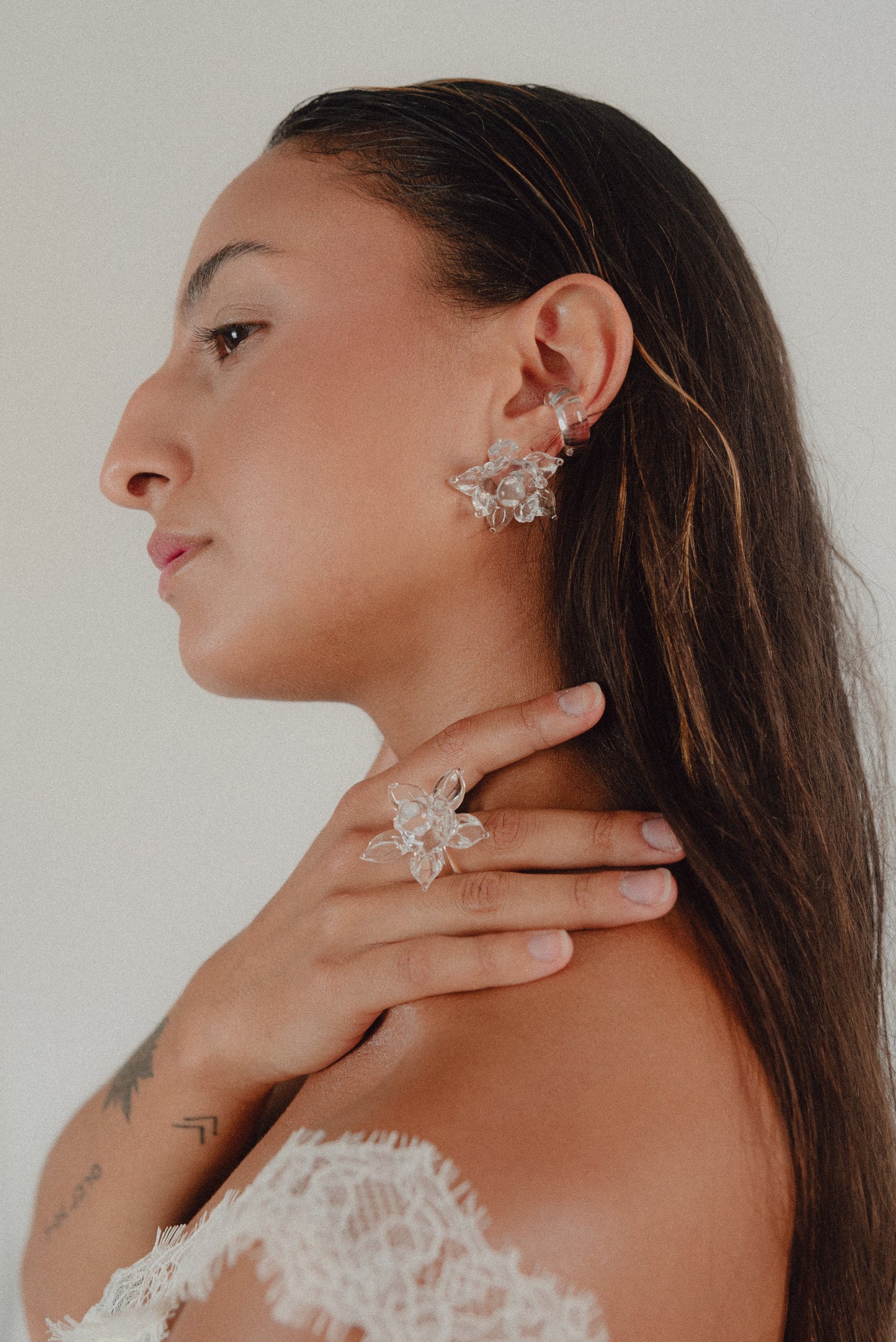 A clear stud Pavonia earring in the shape of a flower with spiky petals, made from recycled glass