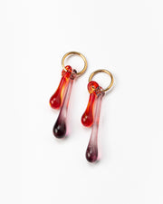 Gold hoop earrings with long red and purple gradient teardrop pendants made from recycled glass