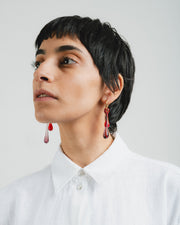 Gold hoop earrings with long red and purple gradient teardrop pendants made from recycled glass