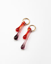 Gold hoop earrings with long red and purple gradient teardrop pendants made from recycled glass