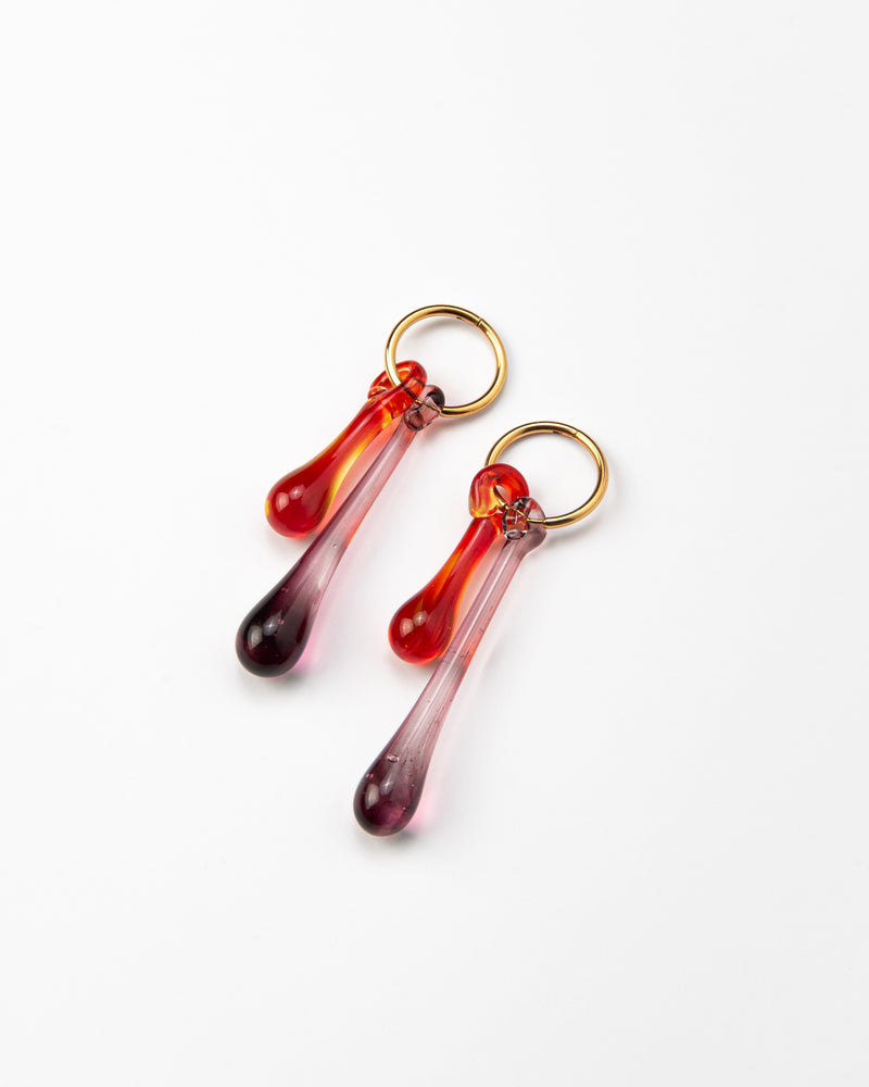 Gold hoop earrings with long red and purple gradient teardrop pendants made from recycled glass