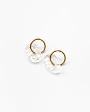 A pair of clear, transparent oval earrings on a golden hoop, made from recycled glass