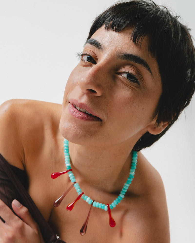 A statement necklace made of turquoise gemstone beads and red recycled glass drop pendants