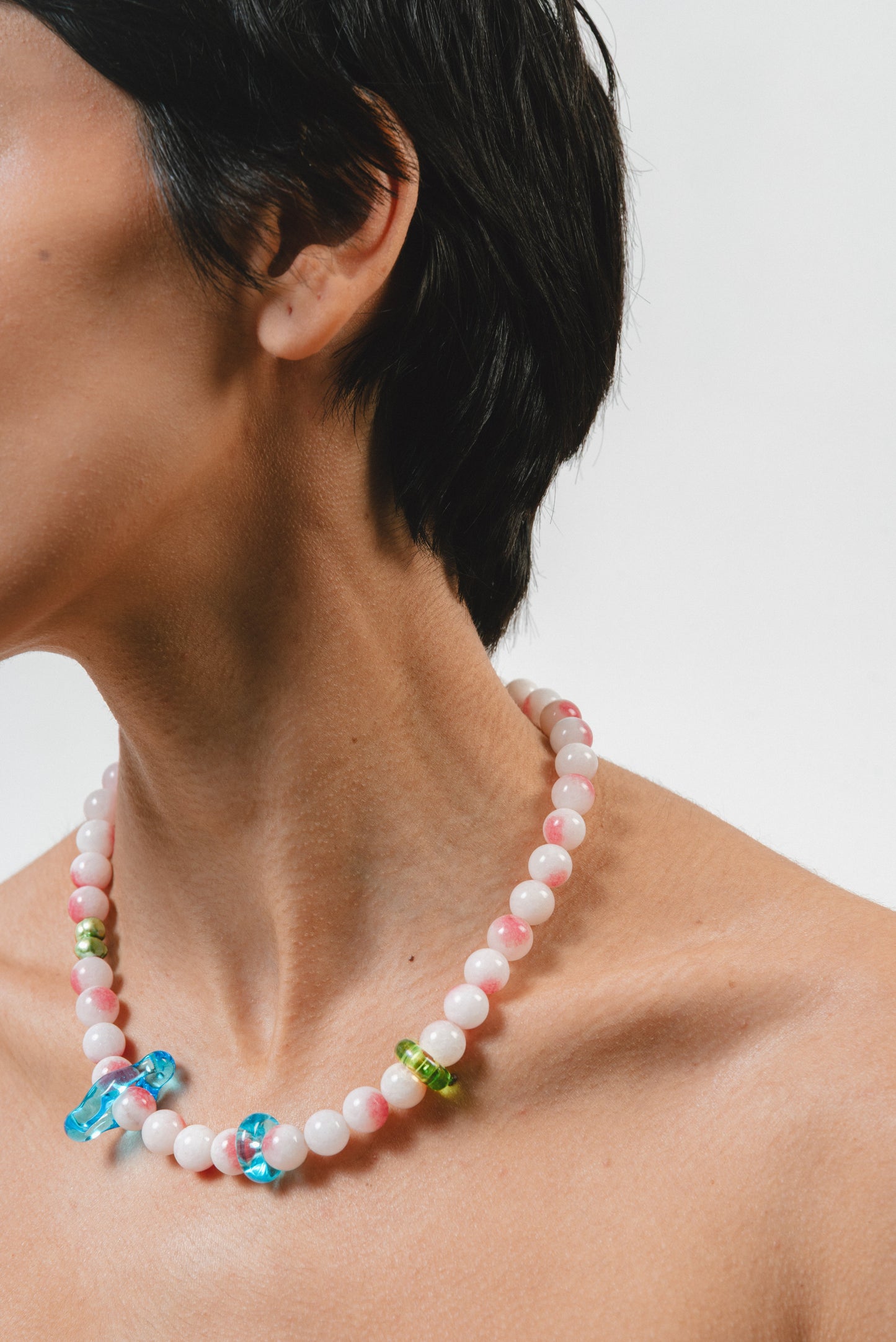 Necklace made of round pink-and-white gemstones, green river pearls and colorful recycled glass accents in blue and green, finished with a silver clasp