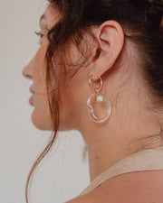 Clear Ameba dangle-hoop earrings on a base of gold stainless steel, with a river pearmade from recycled glass,