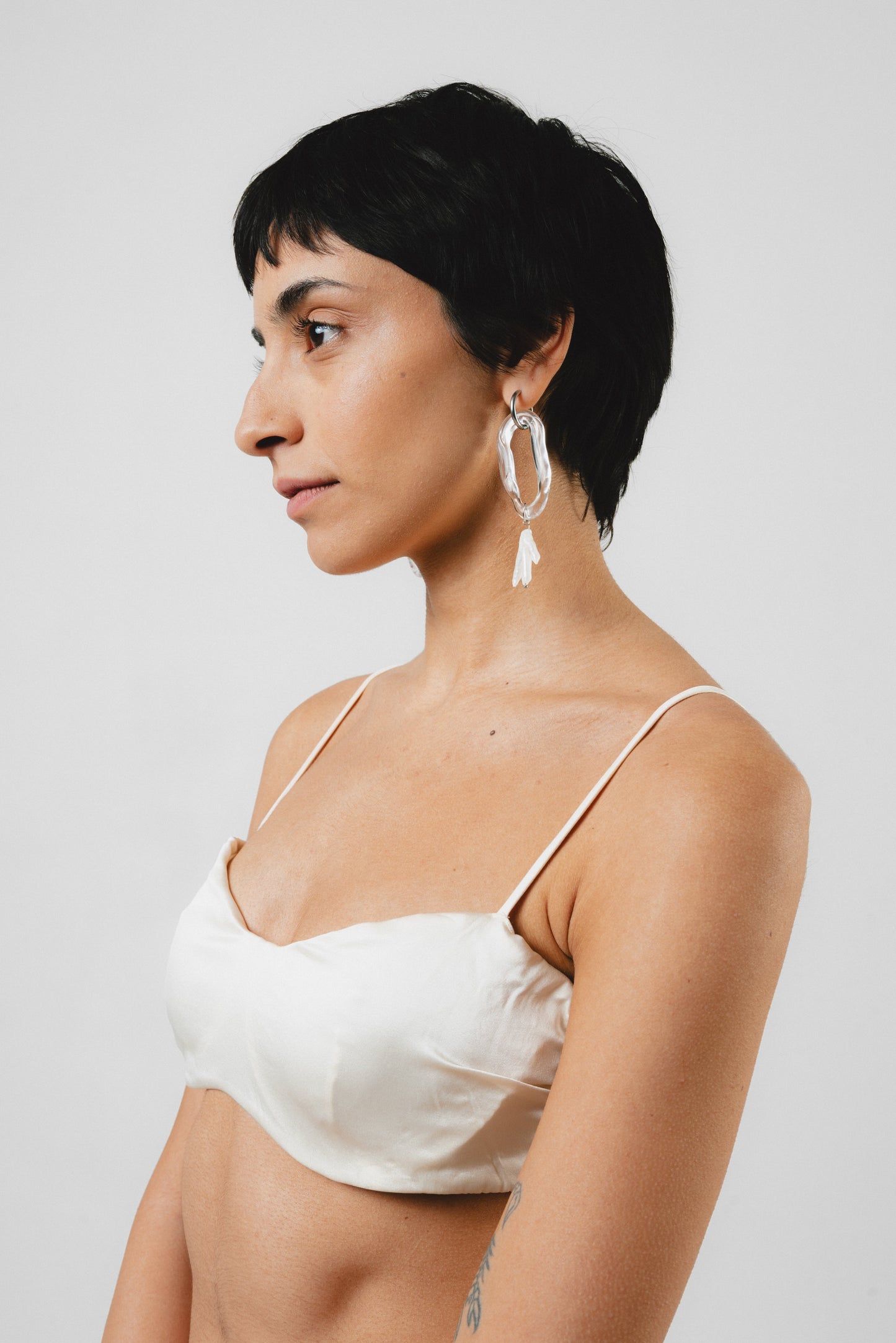 Clear dangle earrings with three pearls on one side, on a base of silver stainless steel, made from recycled glass