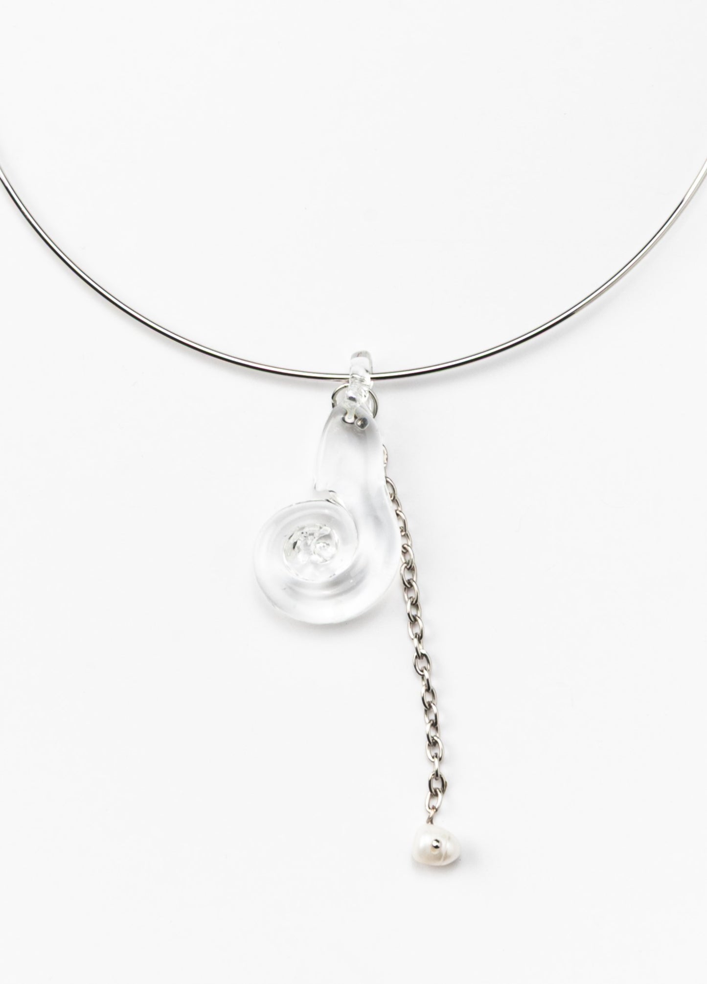 A silver necklace featuring a clear pendant shaped as a shel, made from recycled glass, and a drop chain with a white river pearl at the end