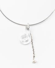 A silver necklace featuring a clear pendant shaped as a shel, made from recycled glass, and a drop chain with a white river pearl at the end