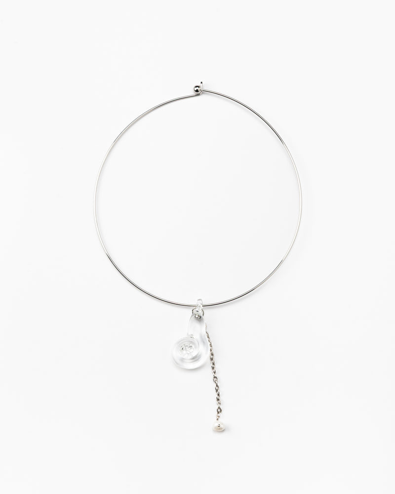 A silver necklace featuring a clear pendant in the shape of a shell, made from recycled glass, and a drop chain with a white pearl at the end