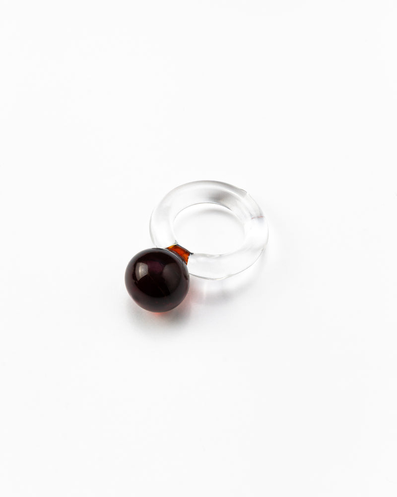 A clear Bolon ring with an amber-coloured sphere on top, handcrafted from recycled glass