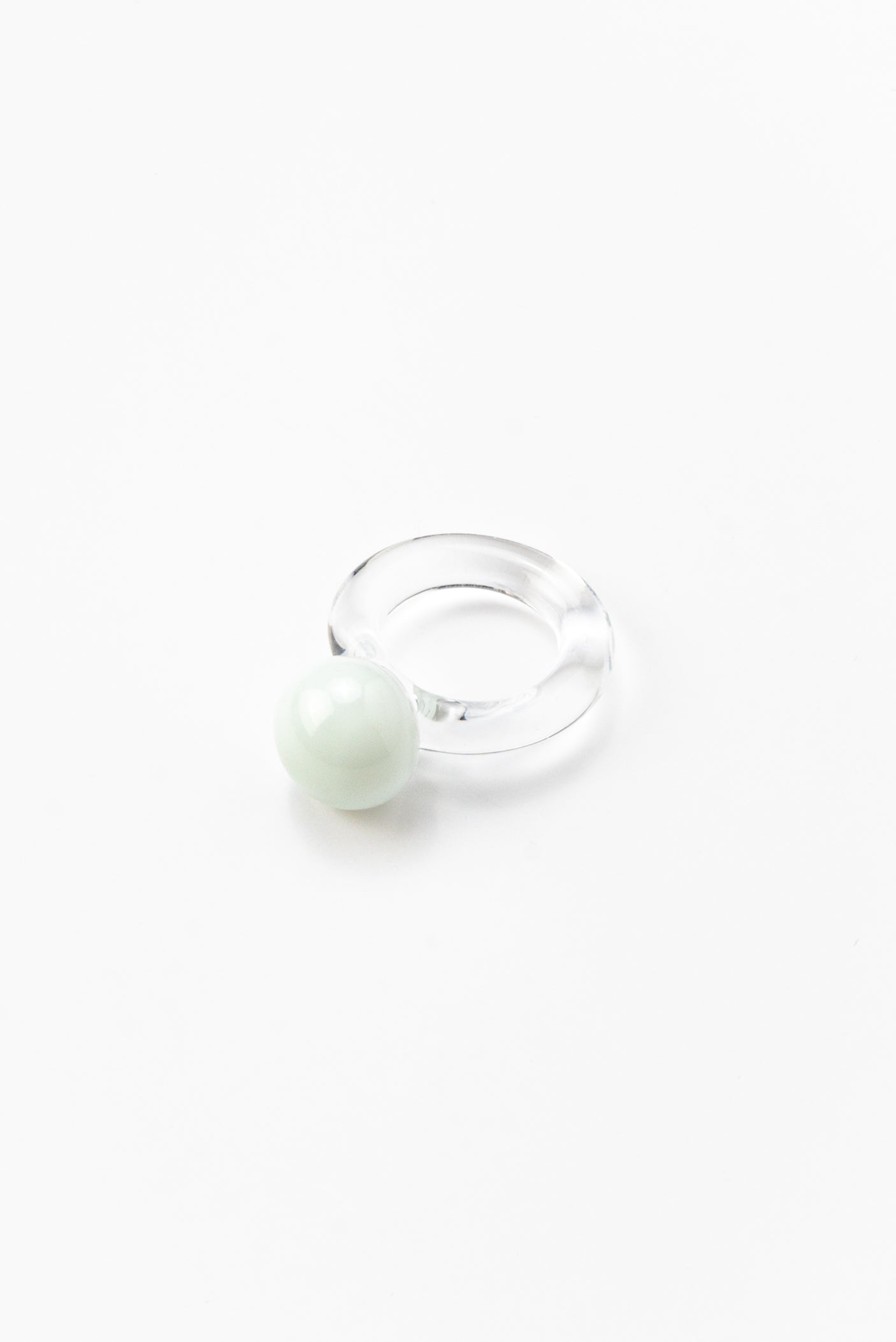 A clear Bolon ring with a white sphere on top, handcrafted from recycled glass