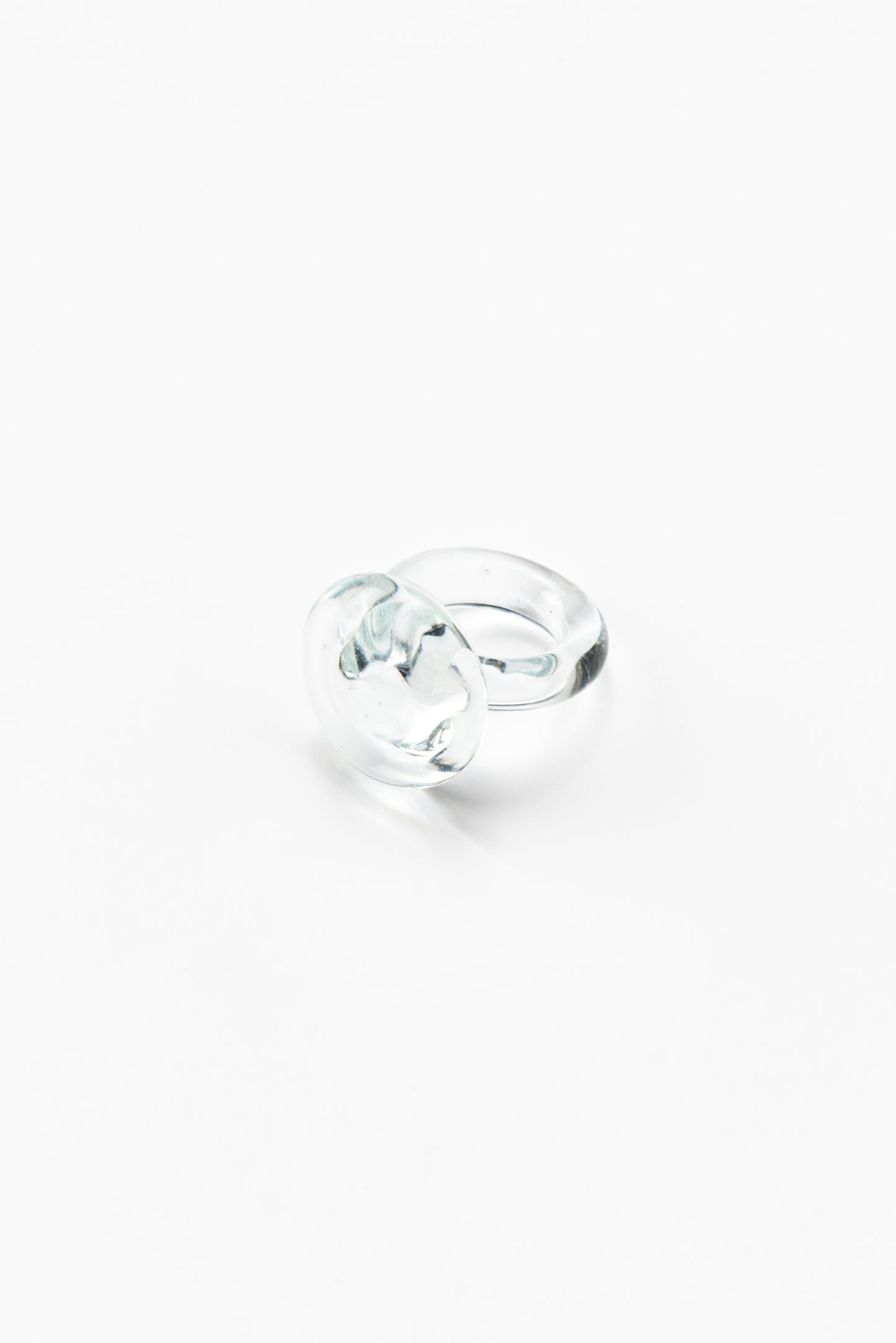 A clear ring featuring a large flat circular glass detail on top, made from recycled glass