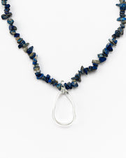 Necklace made of deep blue sea shell beads with a loop-shaped clear recycled glass pendant and a gold toggle clasp