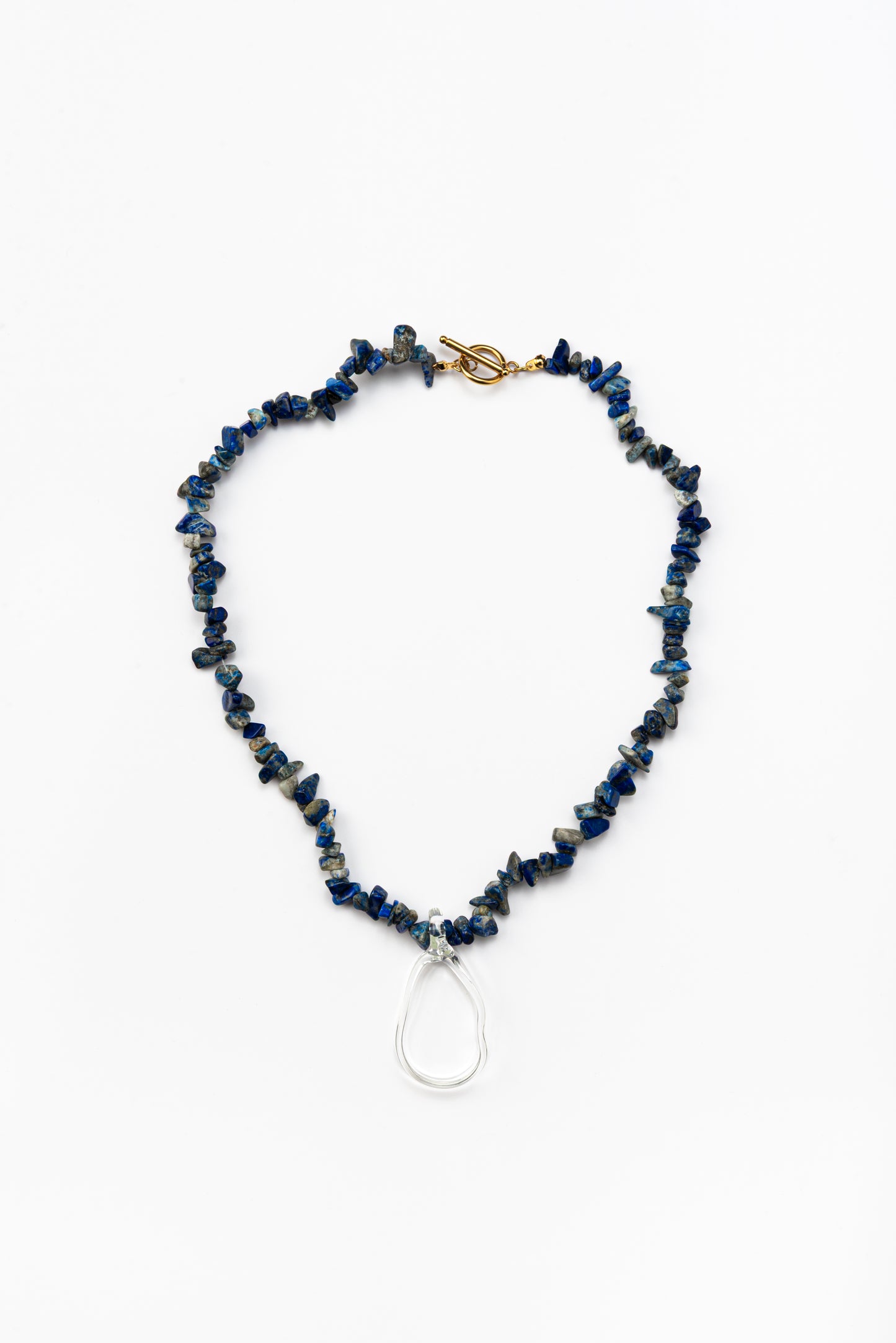 Necklace made of deep blue sea shell beads with a loop-shaped clear recycled glass pendant and a gold toggle clasp