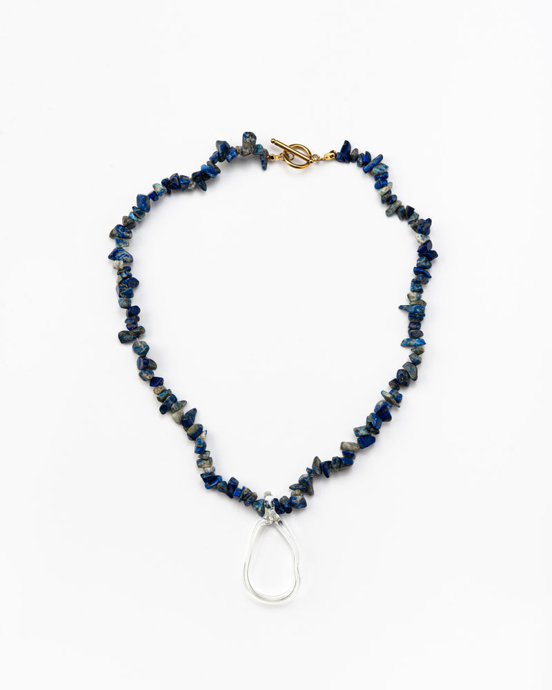 Necklace made of deep blue sea shell beads with a loop-shaped clear recycled glass pendant and a gold toggle clasp
