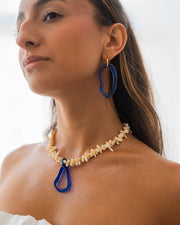 Necklace made of beige sea shell beads with a loop-shaped blue recycled glass pendant and a gold toggle clasp