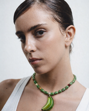 Necklace with green beads and a banana-shaped pendant on a white background