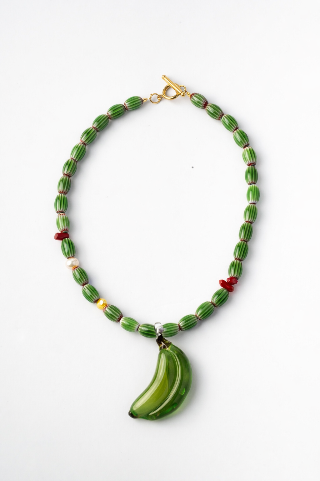 Necklace with green beads and a banana-shaped pendant on a white background