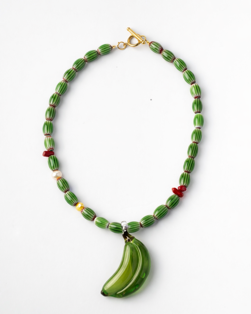 Necklace with green beads and a banana-shaped pendant on a white background