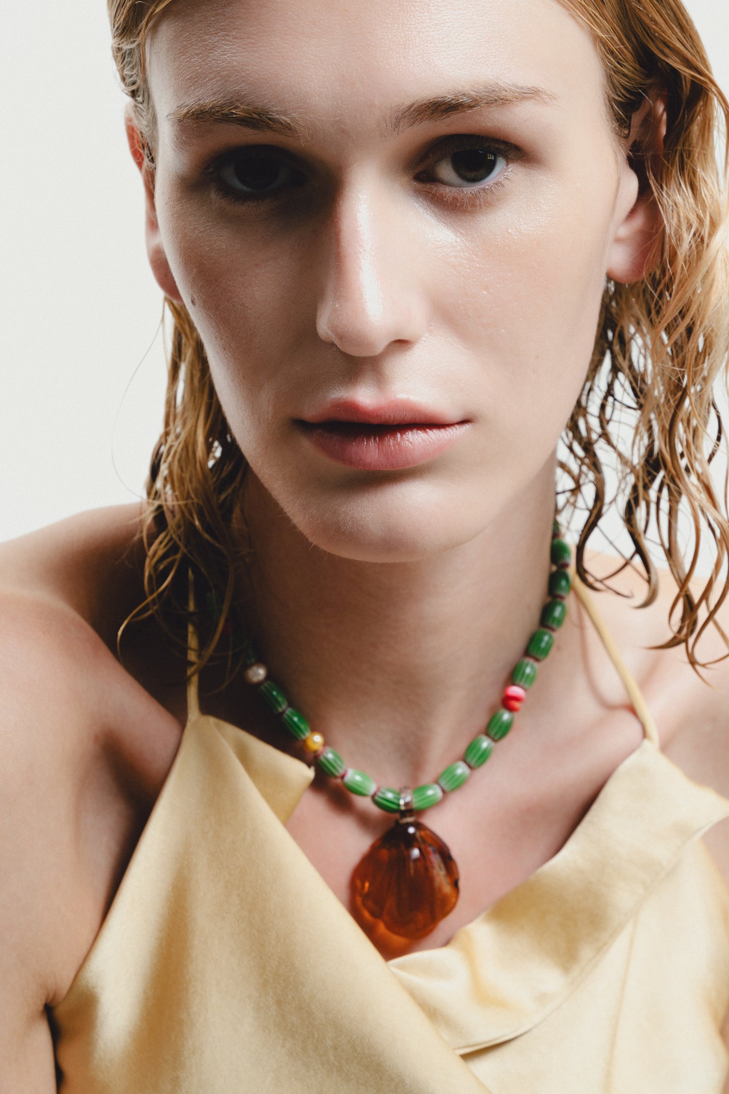 Woman wearing a colorful beaded necklace with a neutral background