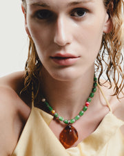 Woman wearing a colorful beaded necklace with a neutral background
