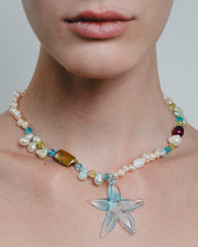 Necklace with starfish pendant worn by a person on a plain background