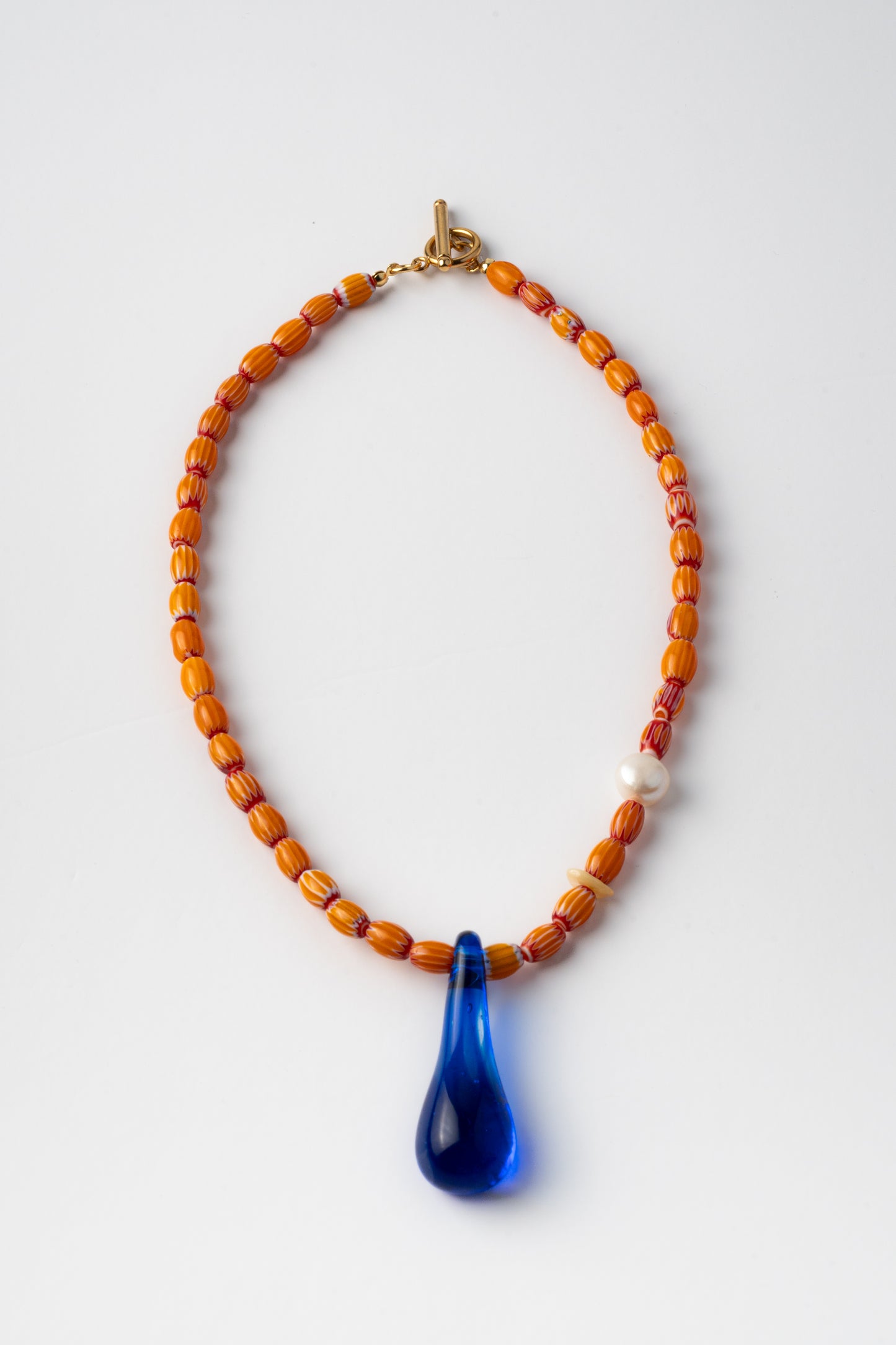 Handmade necklace with orange beads and a blue teardrop pendant 