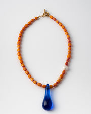 Handmade necklace with orange beads and a blue teardrop pendant 