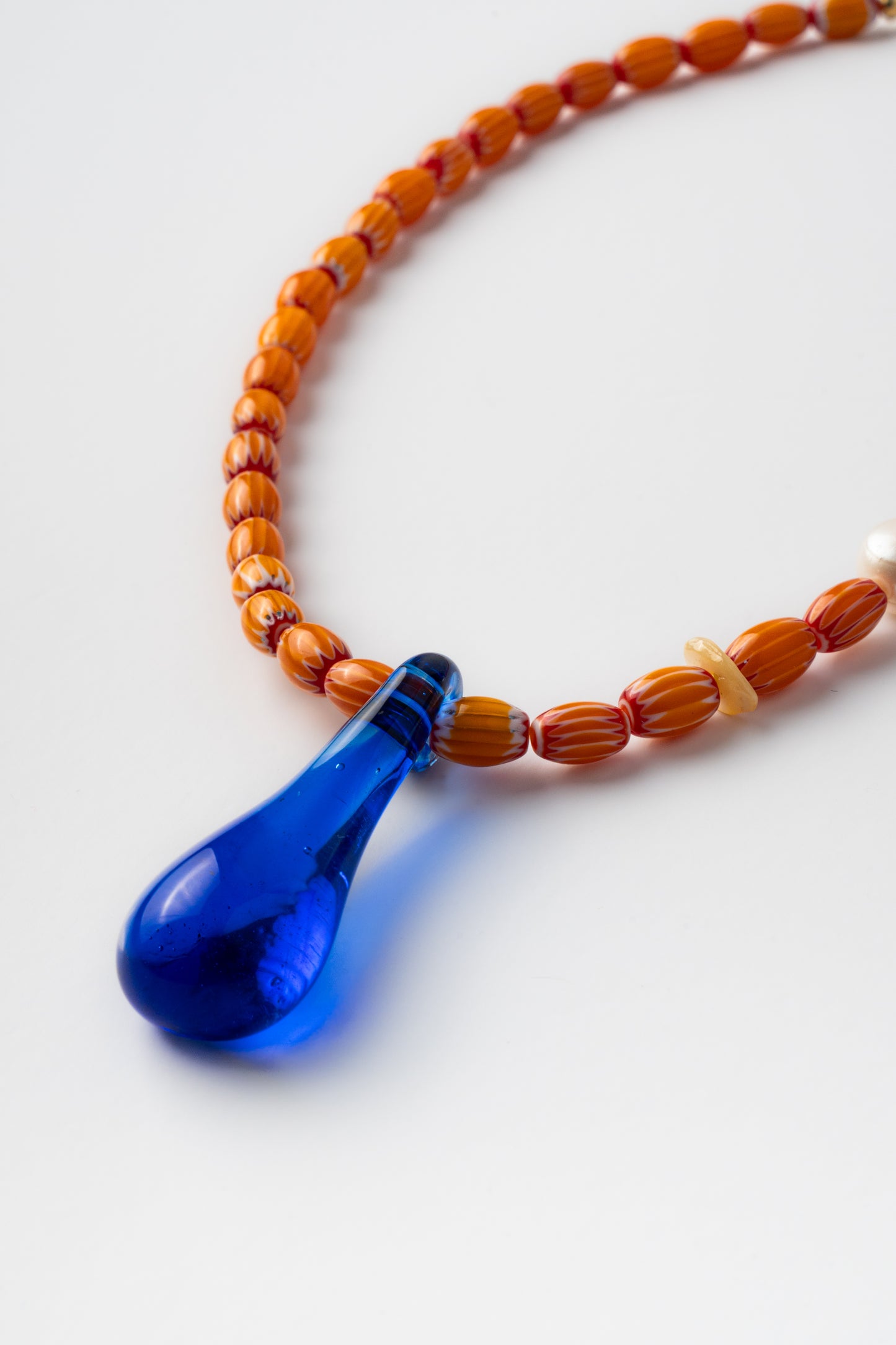 Handmade necklace with orange beads and a blue teardrop pendant 
