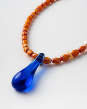 Handmade necklace with orange beads and a blue teardrop pendant 