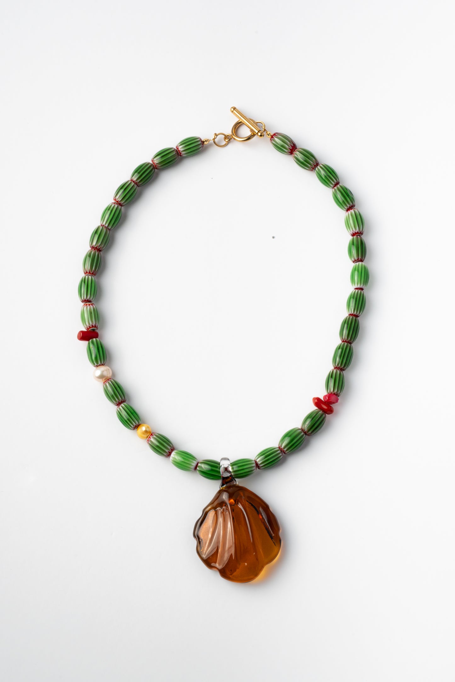 Colorful handmade necklace with green beads and a large amber pendant 