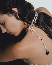 Woman wearing a delicate pearl necklace with a white background