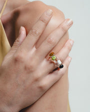Close-up of a hand wearing a ring with colorful beads on a neutral background