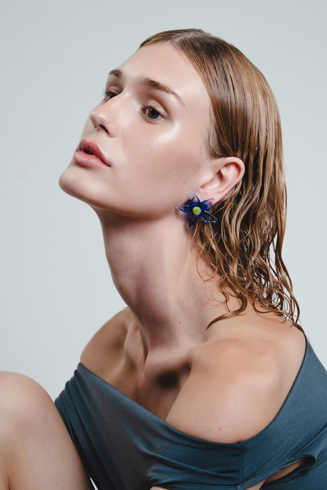 Woman wearing a blue top and floral earrings against a light gray background