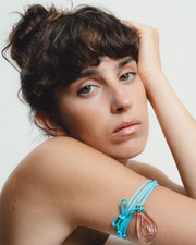 Turquoise cord necklace with a teardrop pendant on a white background