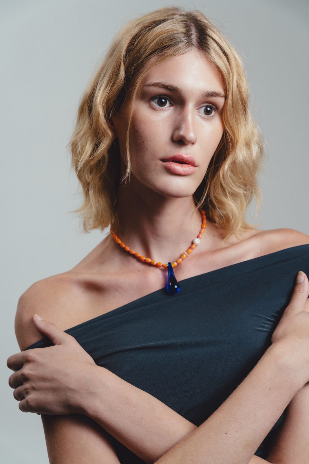 Handmade necklace with orange beads and a blue teardrop pendant 