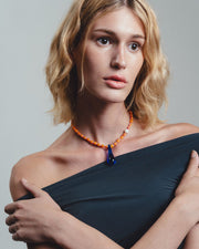 Handmade necklace with orange beads and a blue teardrop pendant 