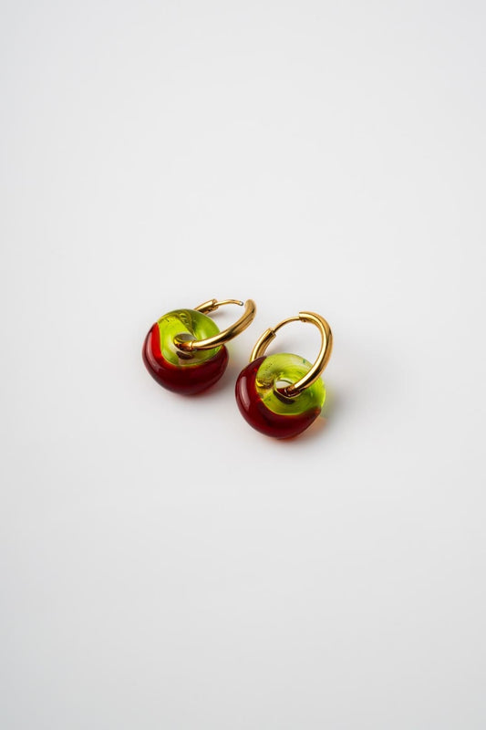Pair of earrings with red and green circular charms on a white background