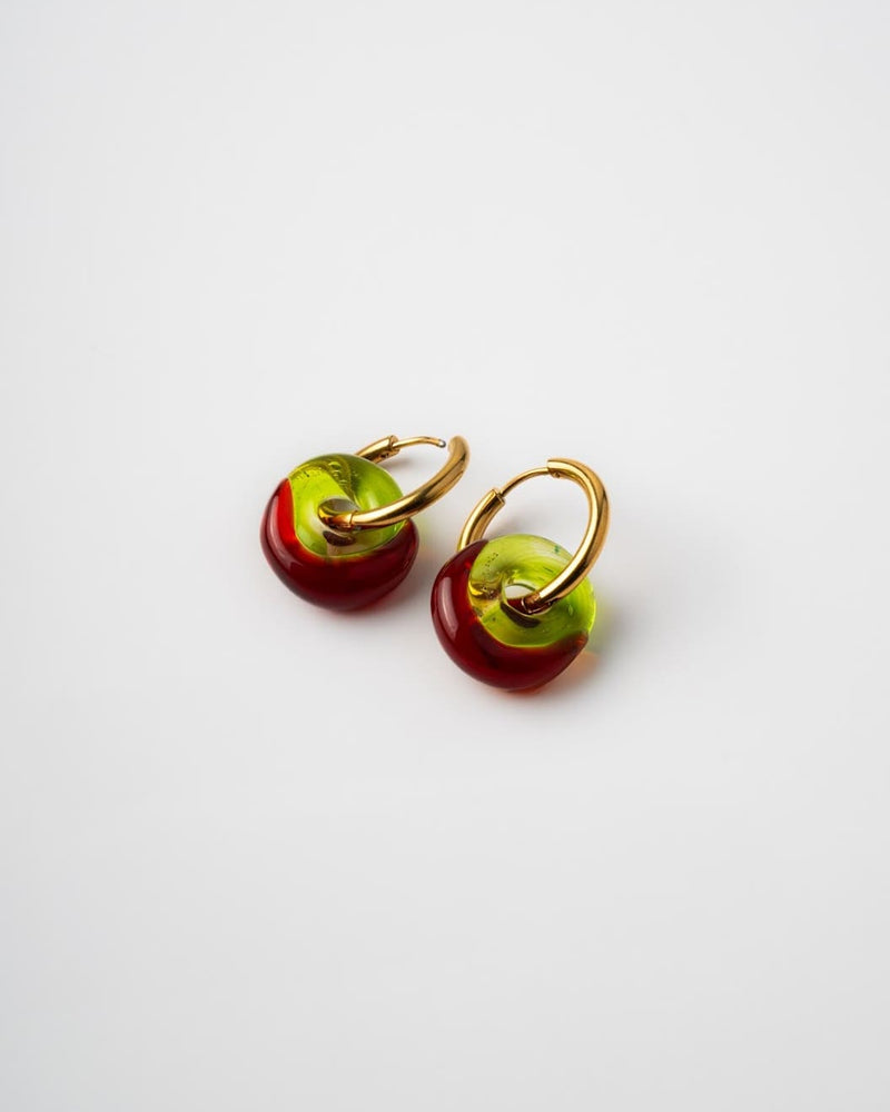 Pair of earrings with red and green circular charms on a white background