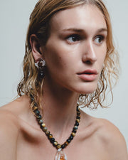 Woman wearing a beaded necklace with a pendant against a neutral background