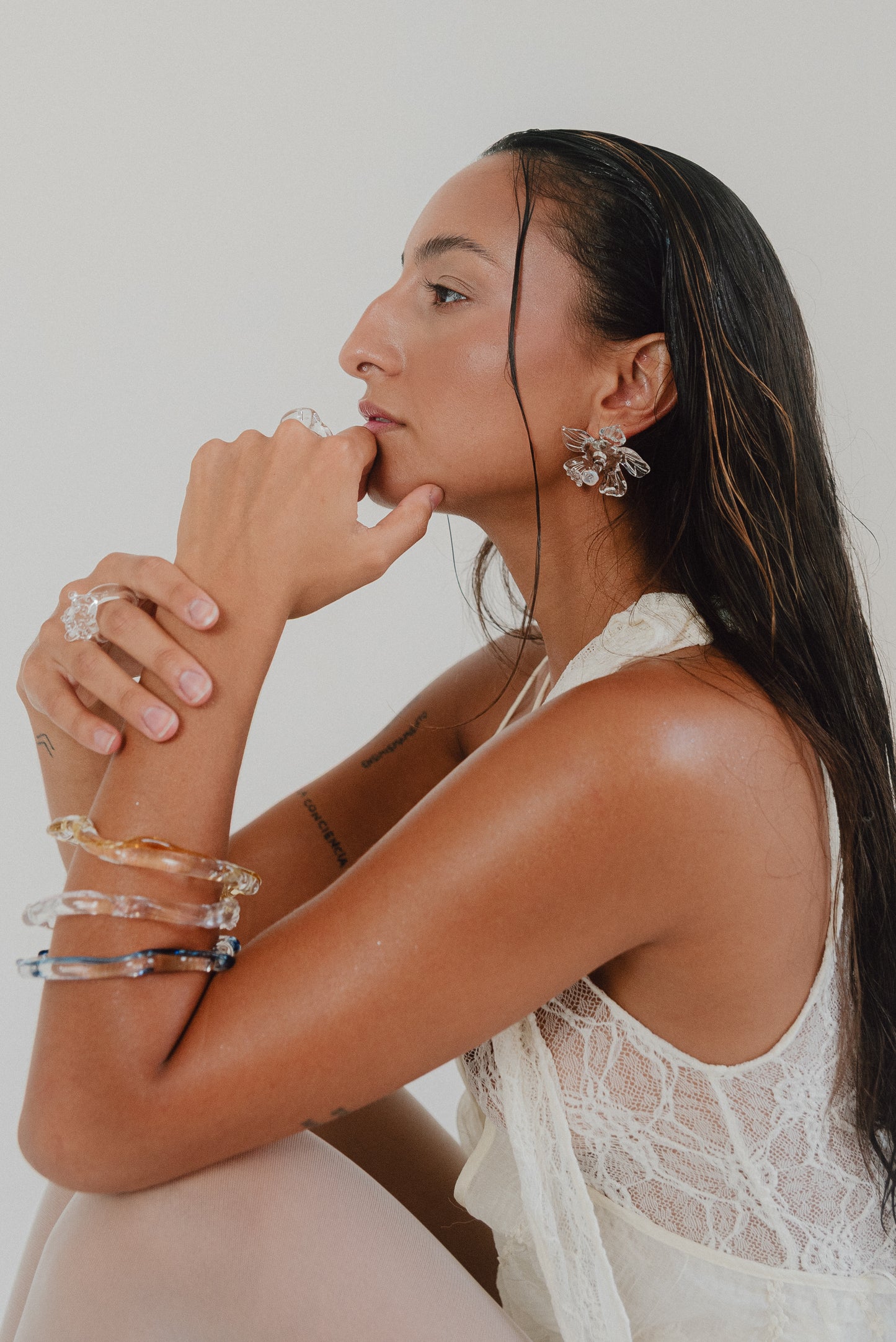 Wavy-shaped bracelets made of clear recycled glass with subtle pink, yellow, and blue accents