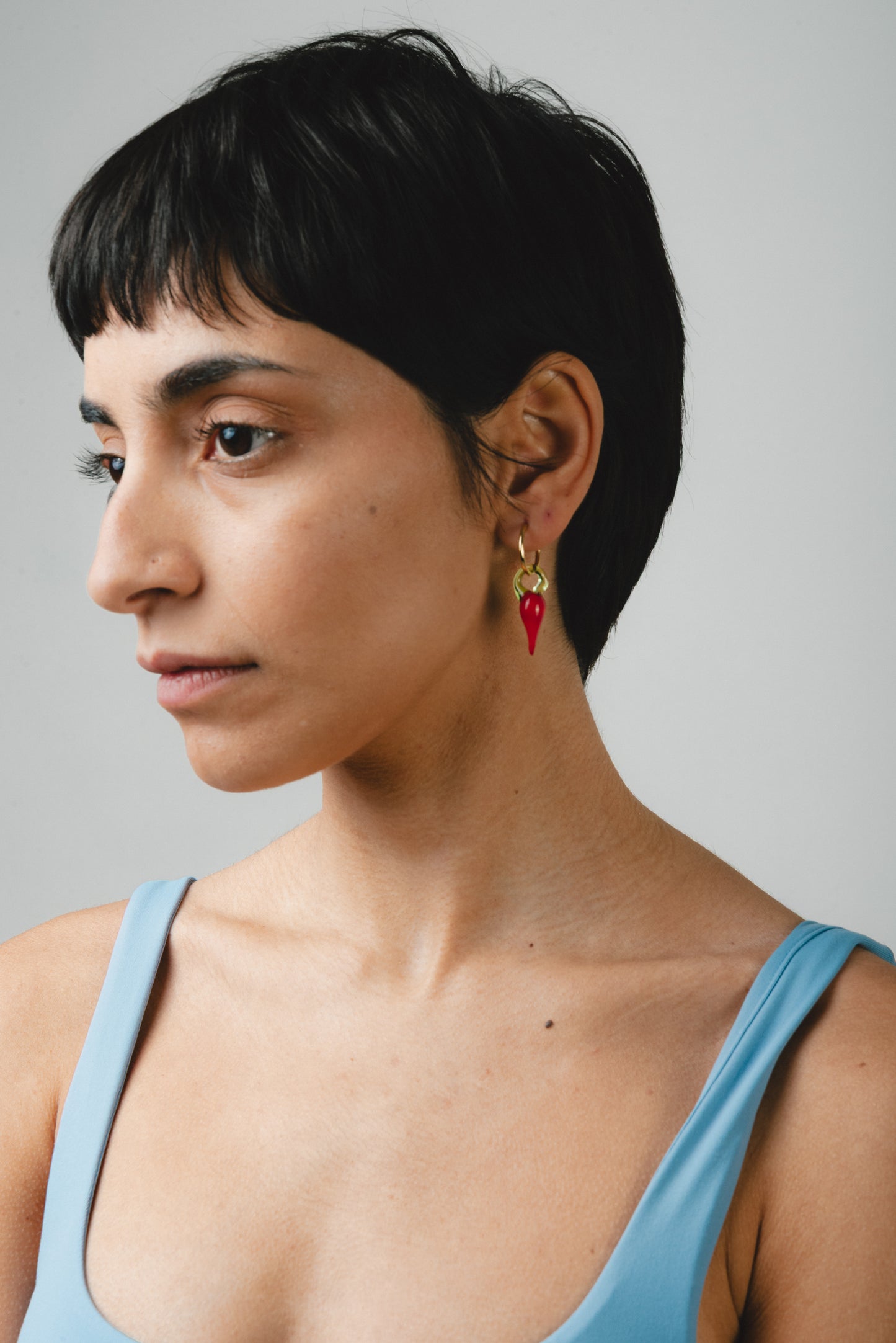 Gold hoop earrings with red chili pepper-shaped pendants made from recycled glass