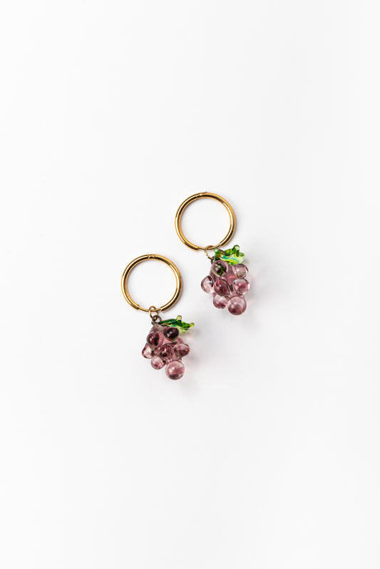 Gold hoop earrings with purple grape-shaped pendants with green leaves, handcrafted from recycled glass.