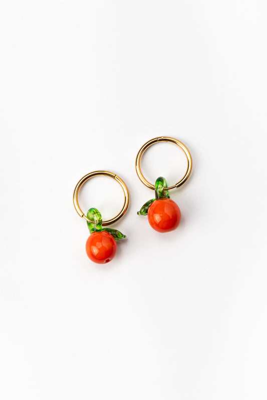 Gold hoop earrings featuring handcrafted orange-shaped charms made from recycled glass, detailed with delicate green leaves.