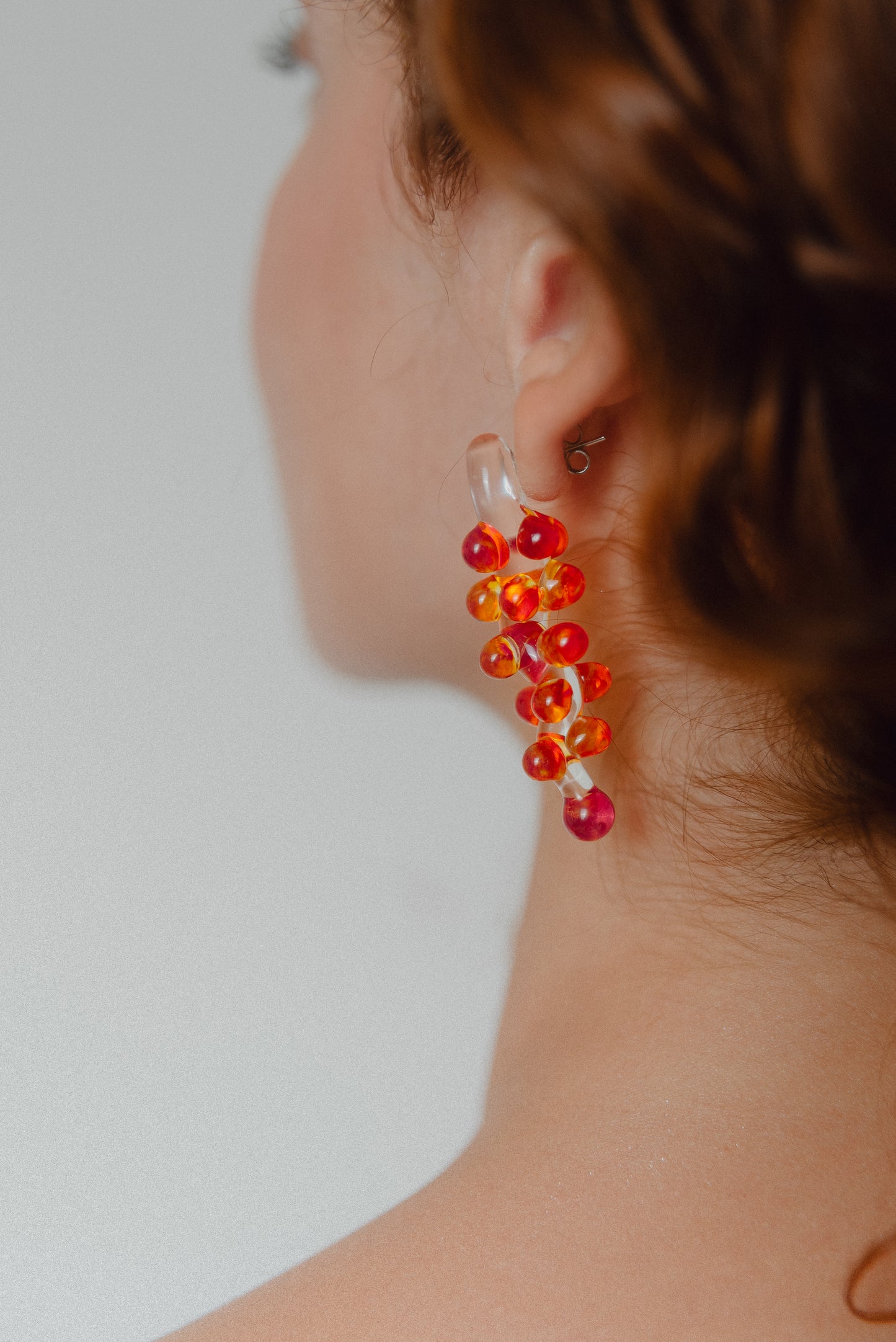 Dangle earrings with red sphere clusters and clear studs, made from recycled glass.