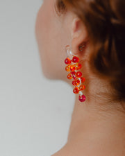 Dangle earrings with red sphere clusters and clear studs, made from recycled glass.