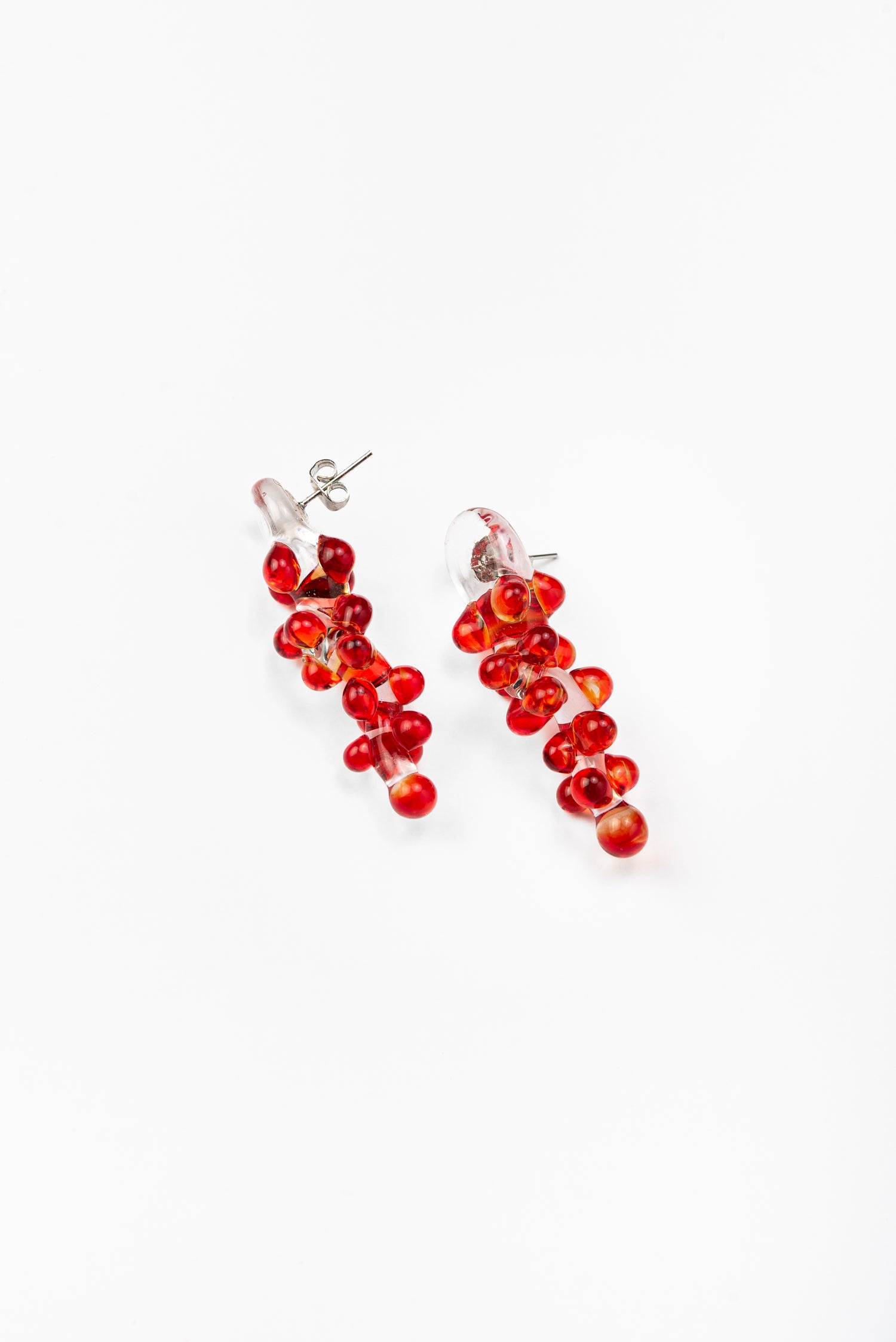 Dangle earrings with red sphere clusters and clear studs, made from recycled glass.