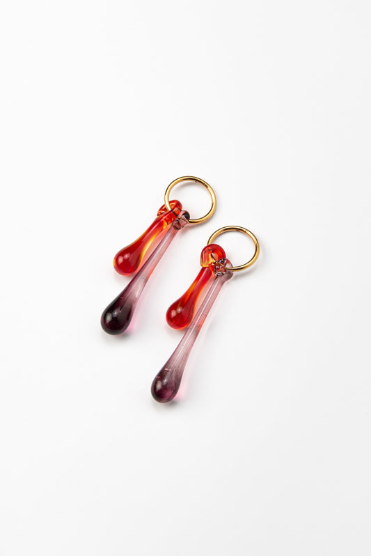 Gold hoop earrings with long red and purple gradient teardrop pendants made from recycled glass