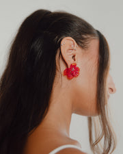 Pair of flower-shaped earrings made from translucent recycled glass in vibrant amber and red tones.